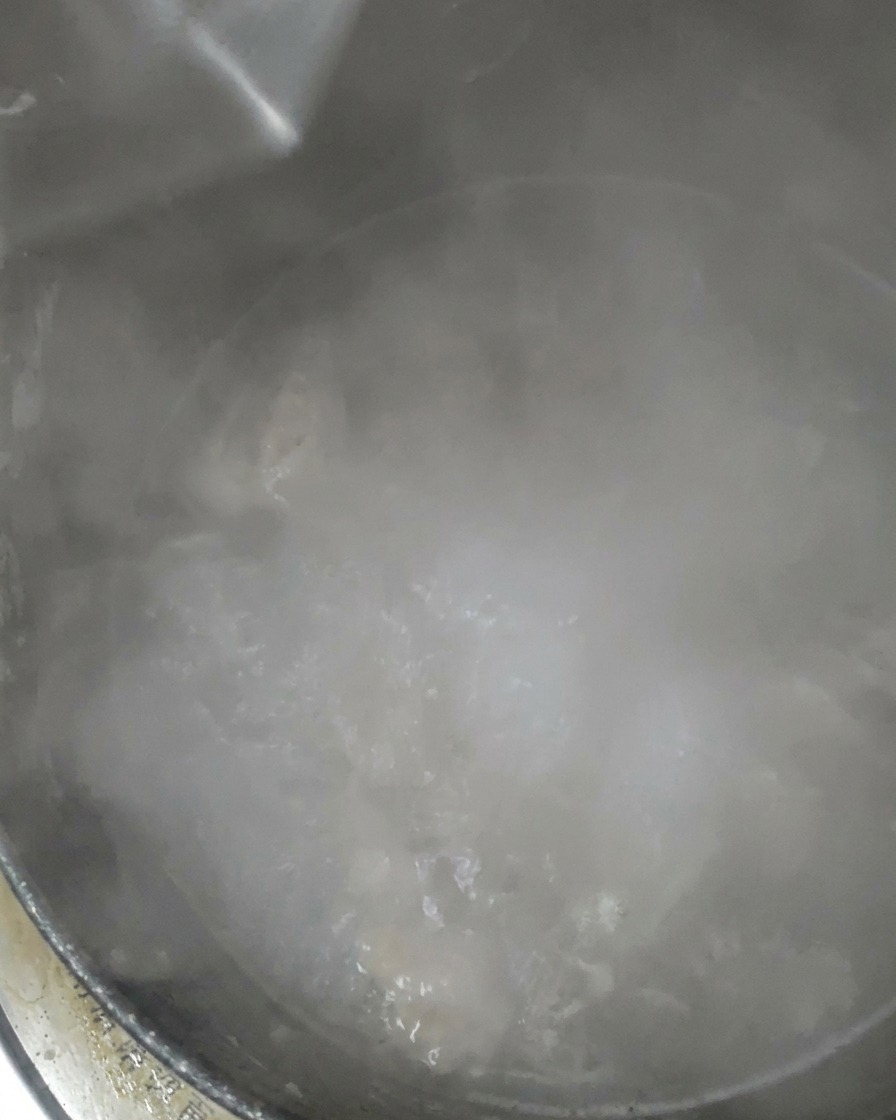 煮立っている鍋にさらに水を加えている様子。