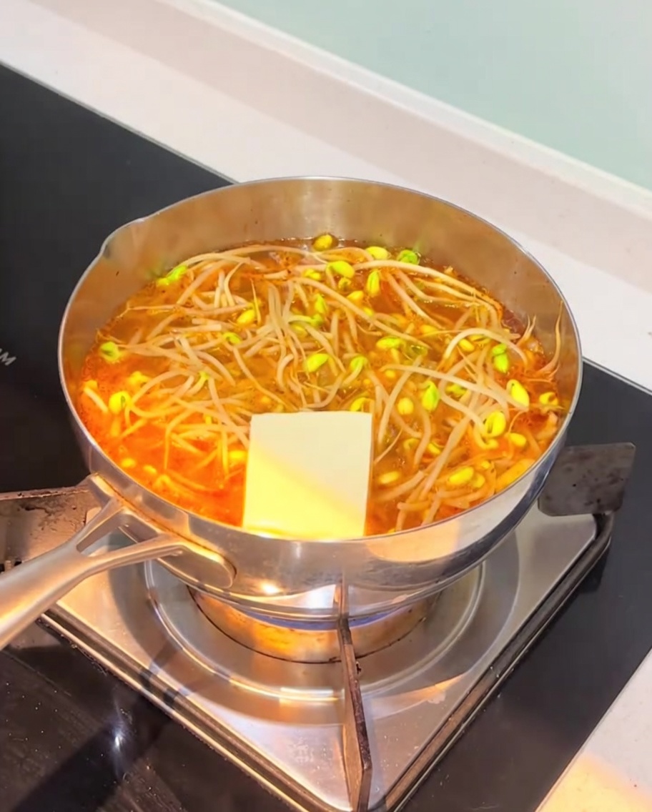 煮立っているチゲに豆腐とさつま揚げを入れている様子。