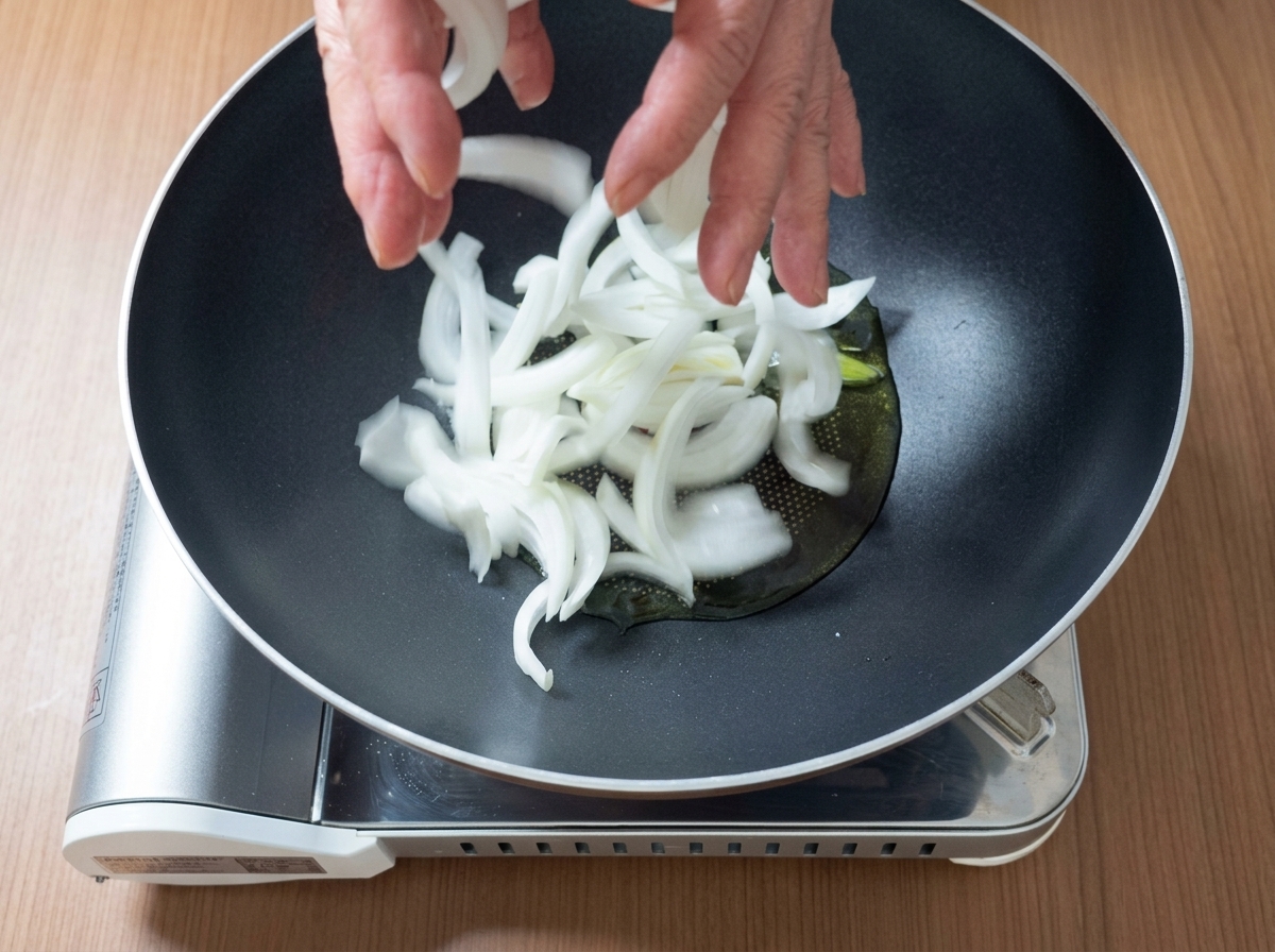 鍋の中でえごま油とアボカドオイルを熱し、豚肉と玉ねぎを炒めている様子。