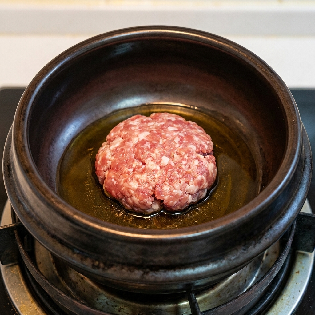 熱した土鍋で豚ひき肉を炒めている様子
