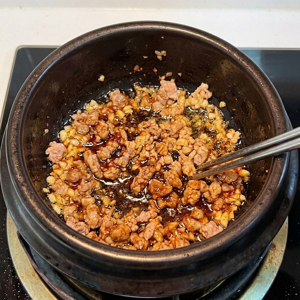 豚肉とキムチを土鍋で一緒に炒めている様子