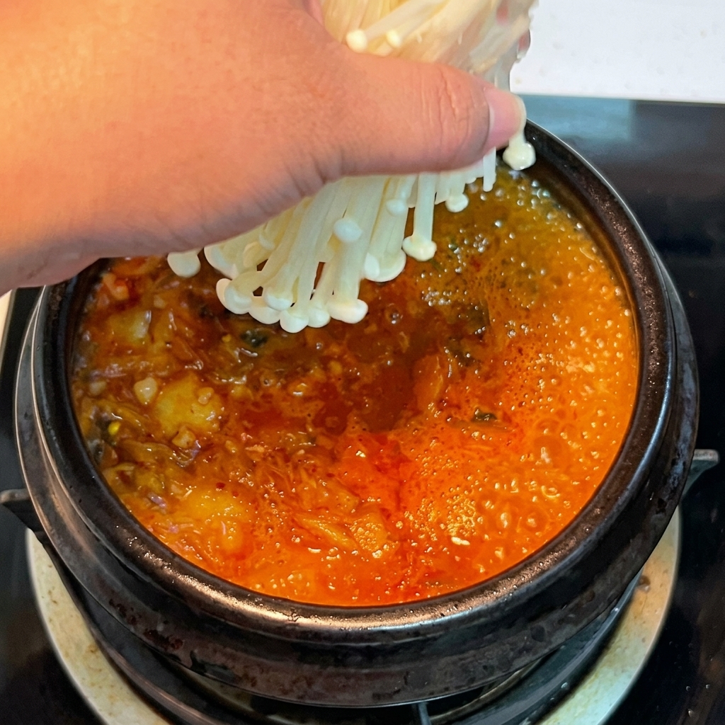 沸騰したスープにえのきを入れている様子