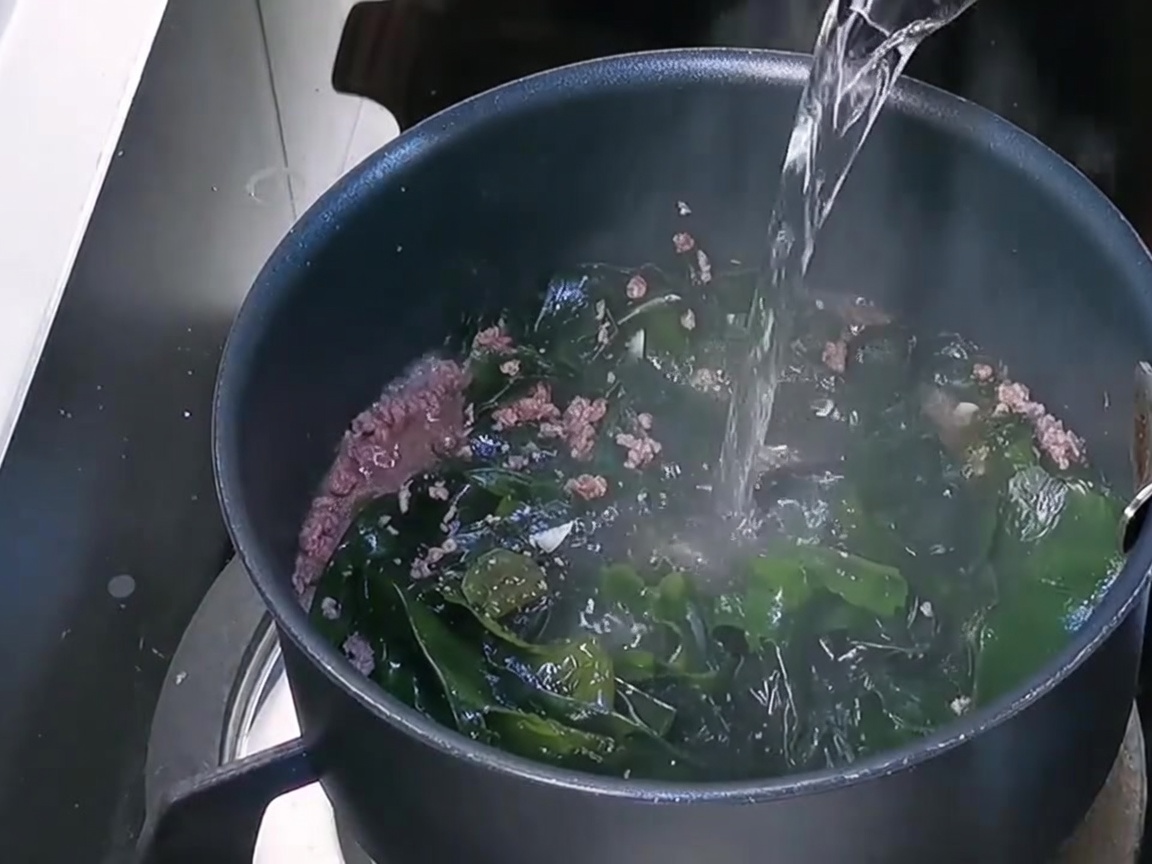 鍋に水を注ぎ入れる様子。
