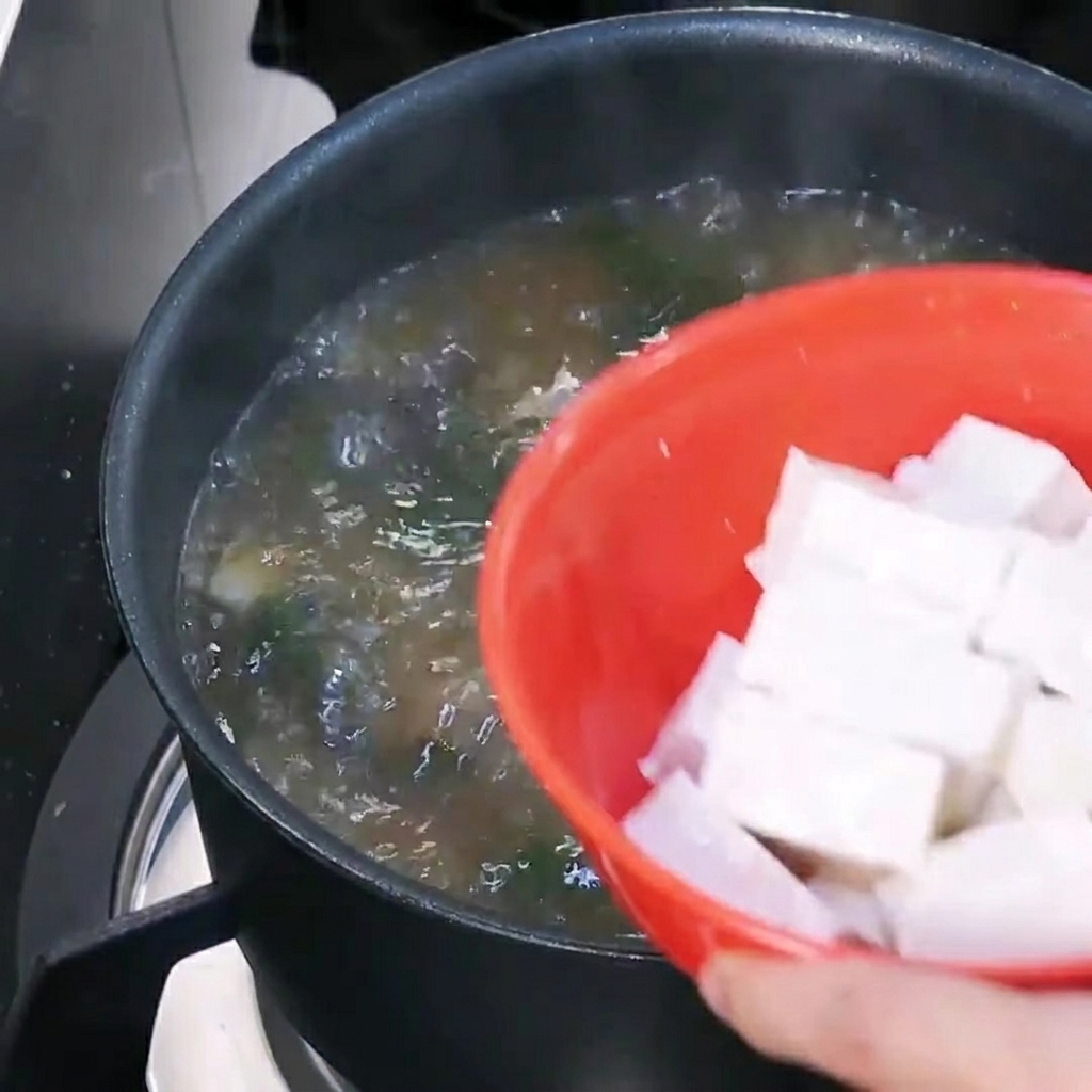 スープに豆腐を加える様子。