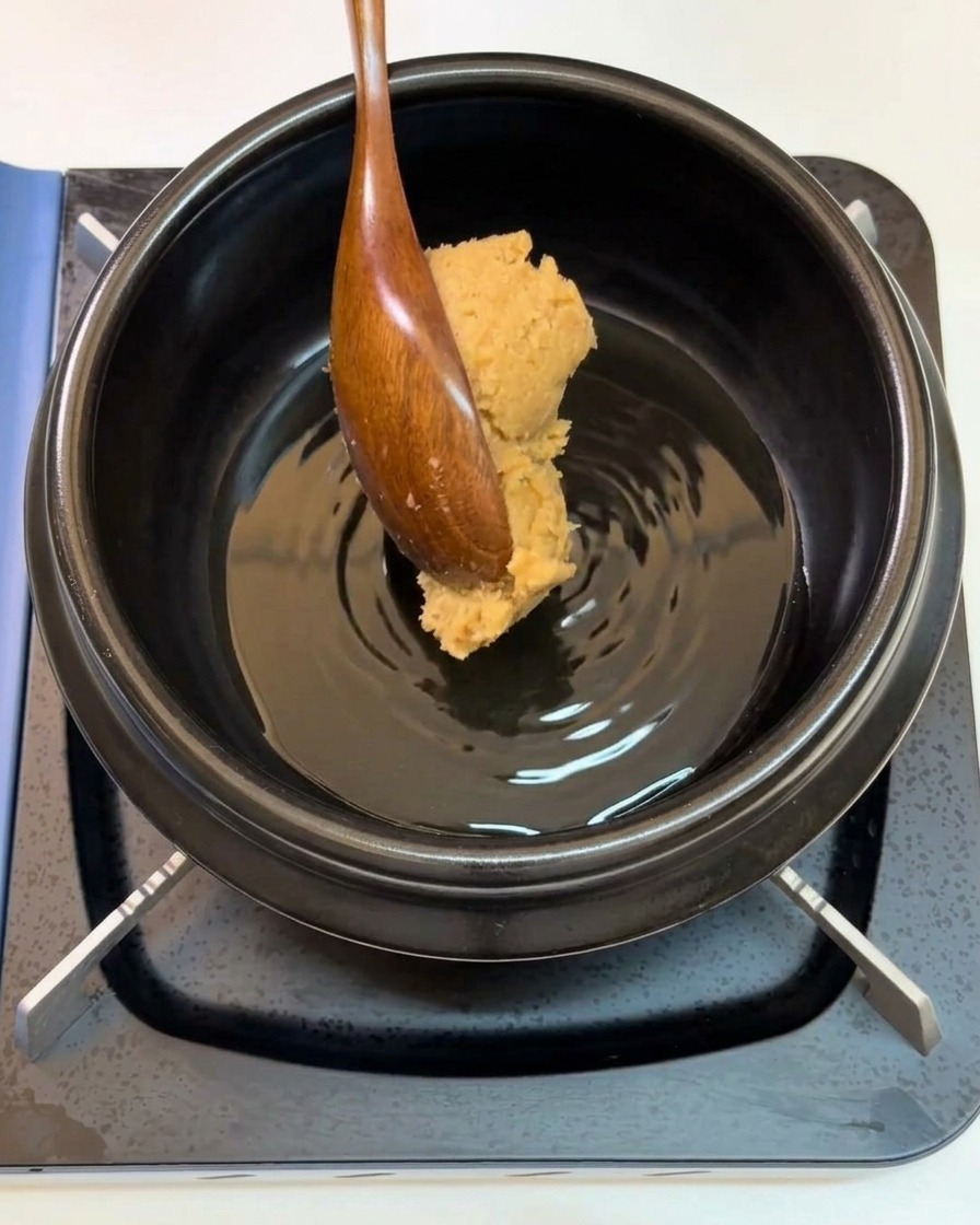 木のスプーンで味噌を鍋に入れる様子。