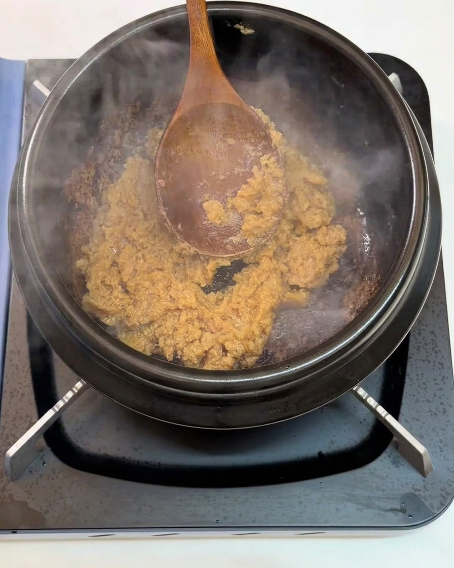 炒めている味噌に刻んだにんにくを加える様子。