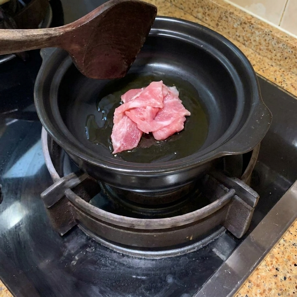 熱した土鍋で油をひき、豚肉を炒めている様子。