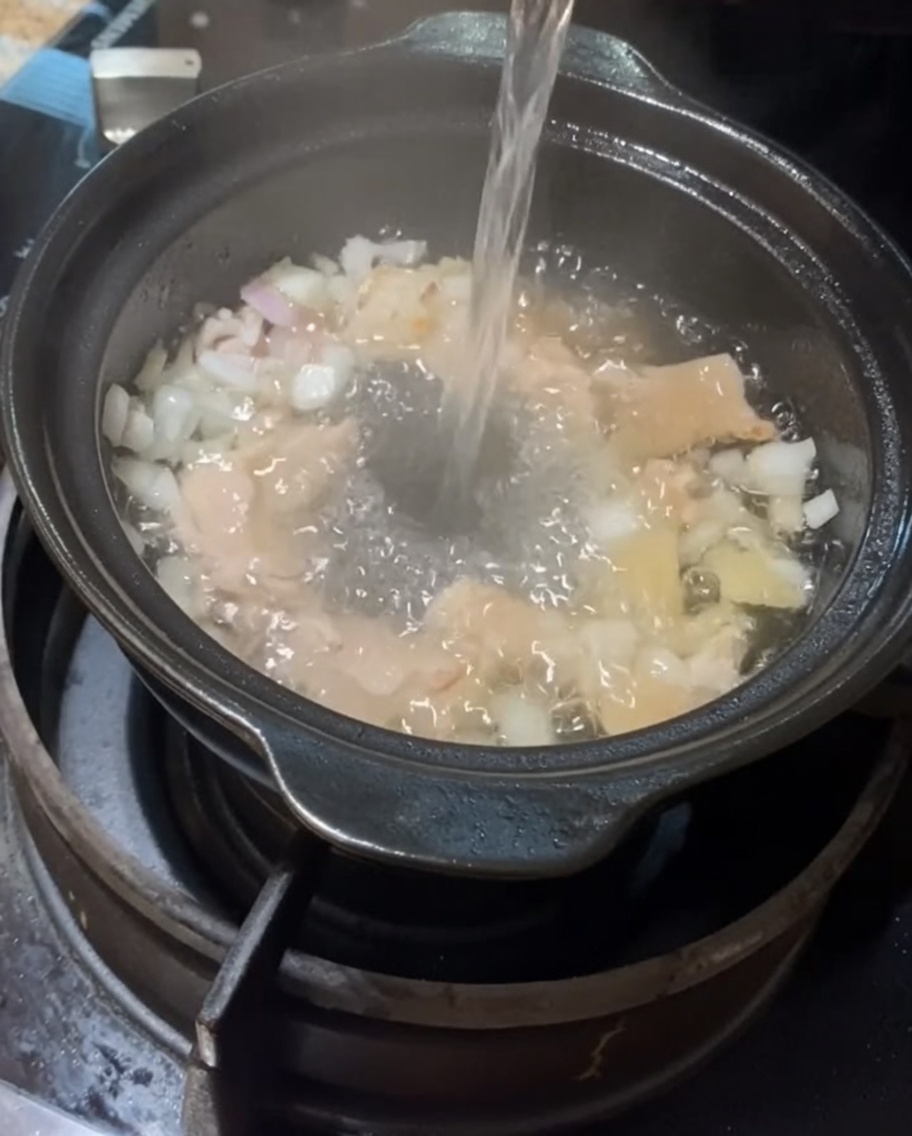 具材が入った土鍋に水を注いでいる様子。