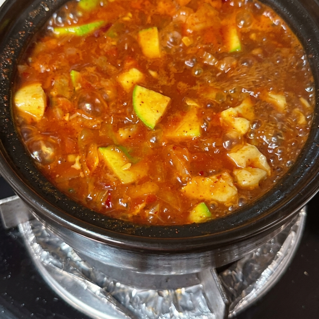 沸騰するスープの中に、薄切り牛肉と生卵が落とされている様子。