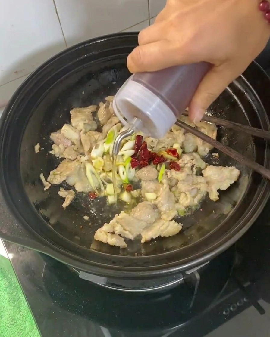 肉と薬味が入った土鍋に料理酒を注ぐ様子。