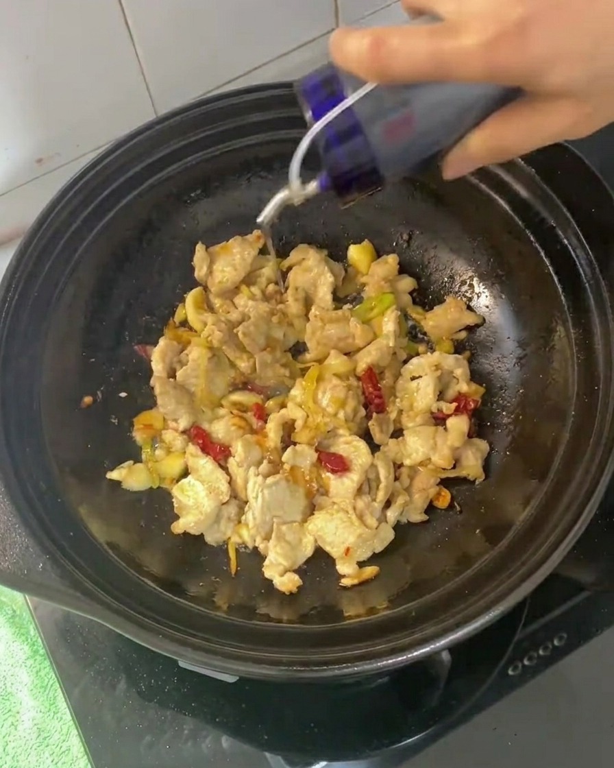 醤油とオイスターソースを土鍋に加えている様子。