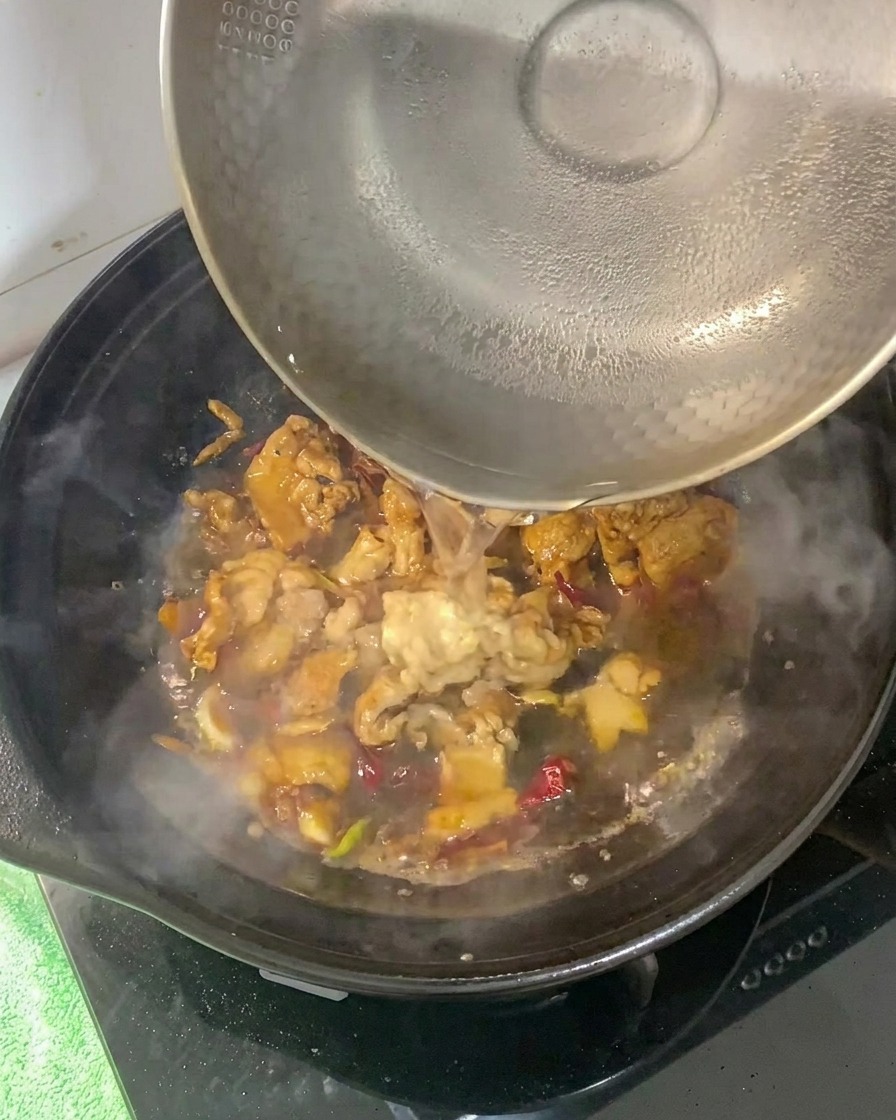 豚肉のベースが入った土鍋に熱湯を注いでいる様子。