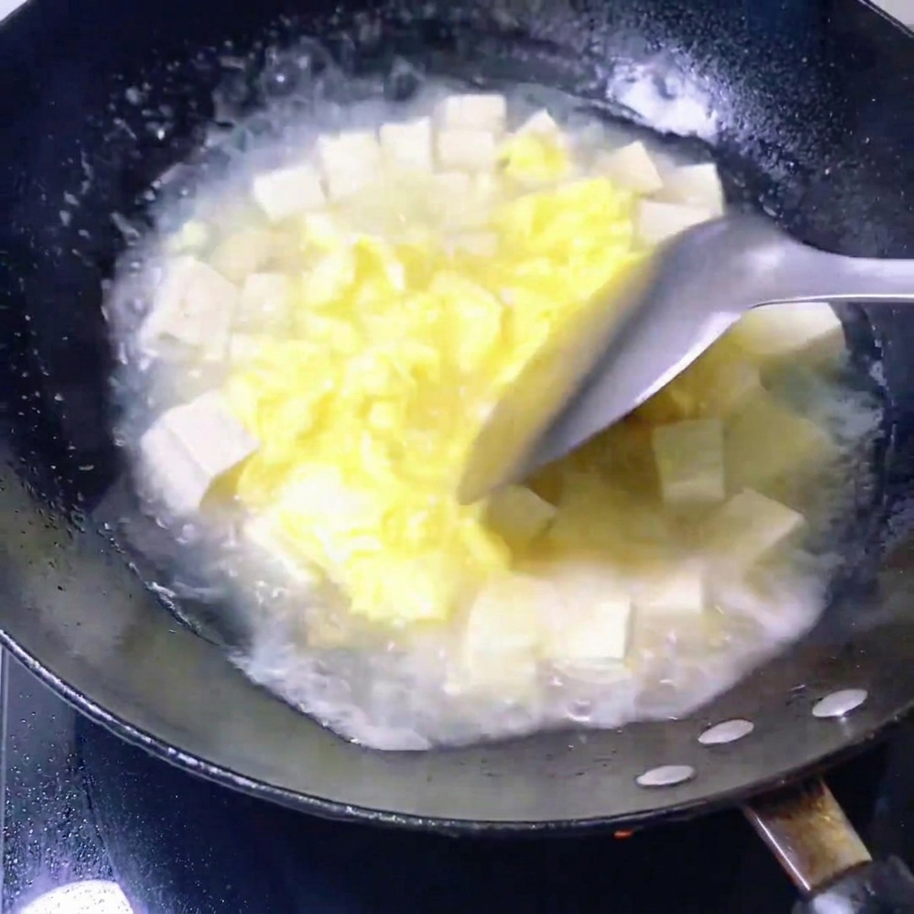 あさりを豆腐とスープが入った鍋に加えている様子。