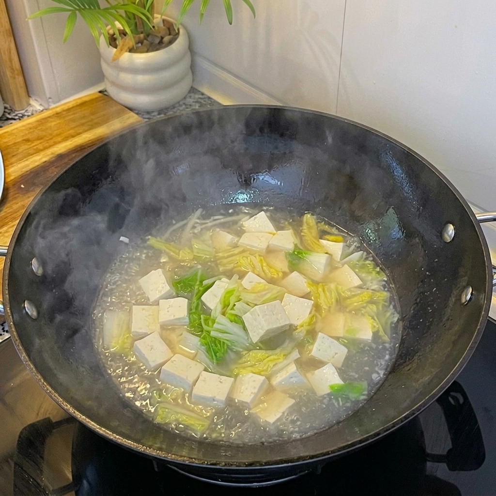 豆腐と卵のスープにあさりを加えて煮ている様子。