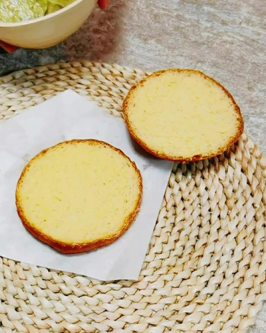 カットしたバンズの断面に緑色のハーブソースを塗っている様子