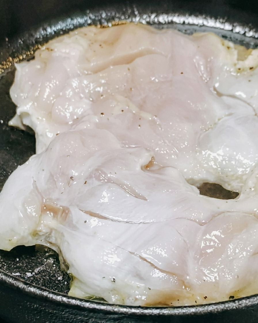 フライパンの鶏肉にソースと白ワインをかけている様子