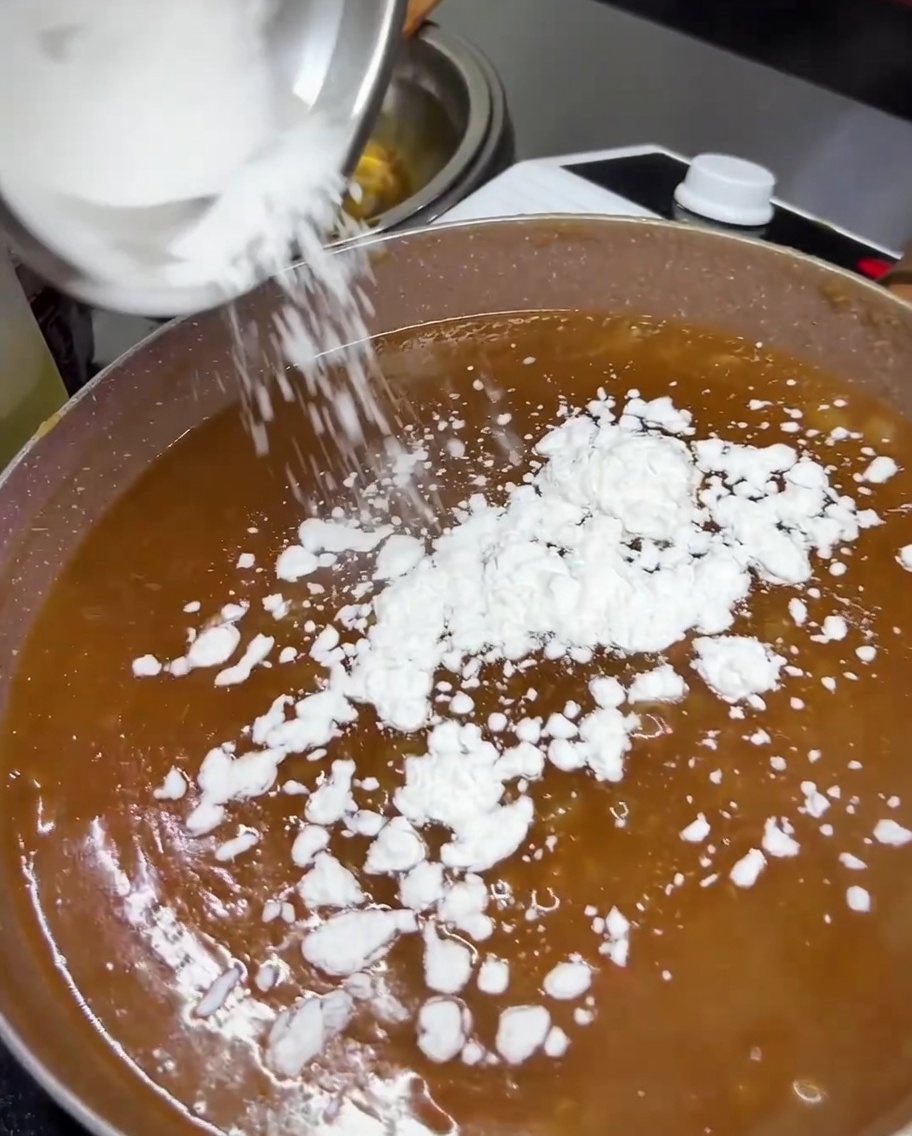 煮立っている照り焼きソースにタピオカ澱粉を振り入れている様子。