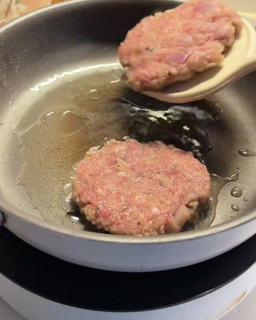 フライパンの中でパティをヘラで裏返している様子