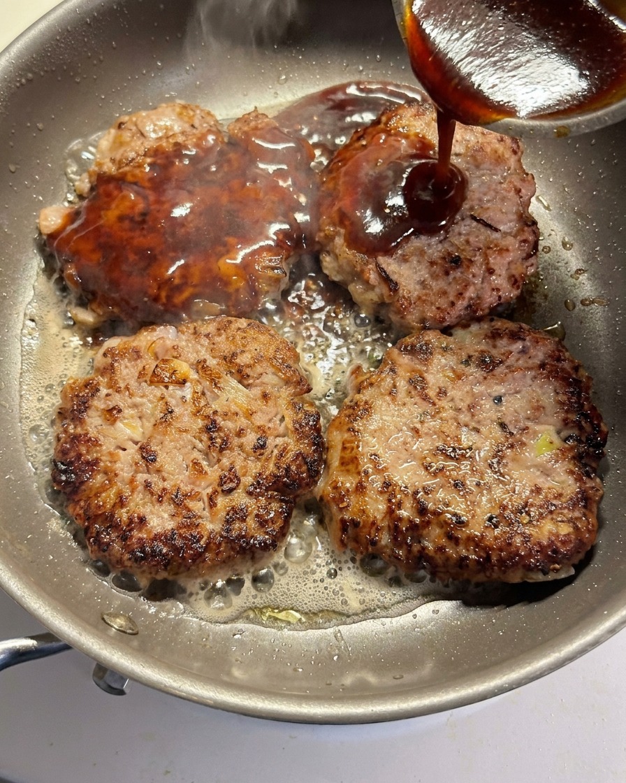 フライパンの中のパティにソースをかけて煮詰めている様子