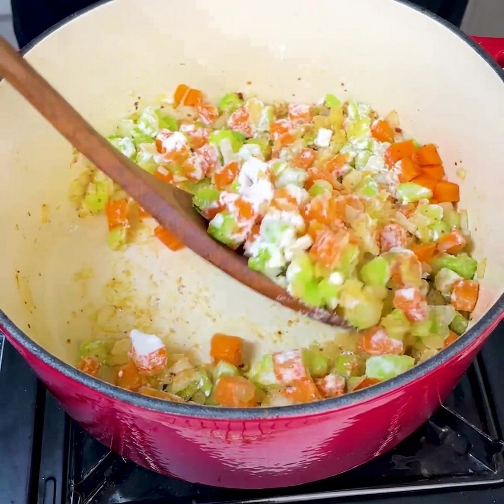 炒めた野菜に小麦粉を加え、しっかりと混ぜ合わせている様子。