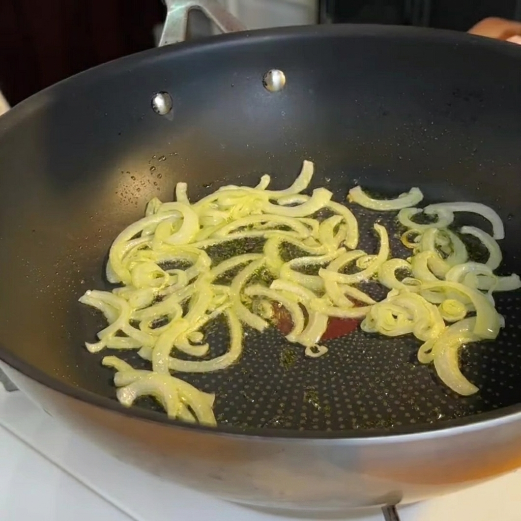 炒めた玉ねぎの入ったフライパンに加えられる、小さく切ったアスパラガスの茎。