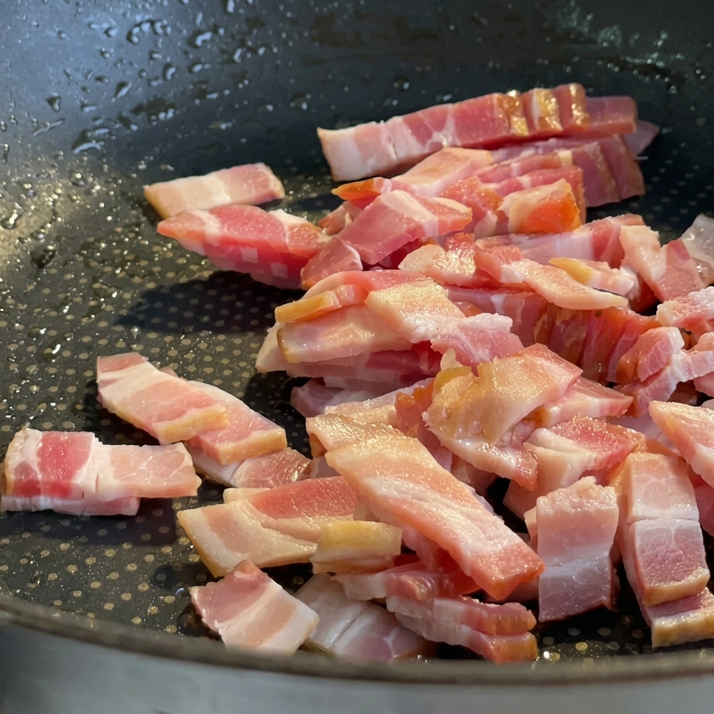フライパンで茶色くカリカリに揚げ焼きされているパンチェッタの欠片。