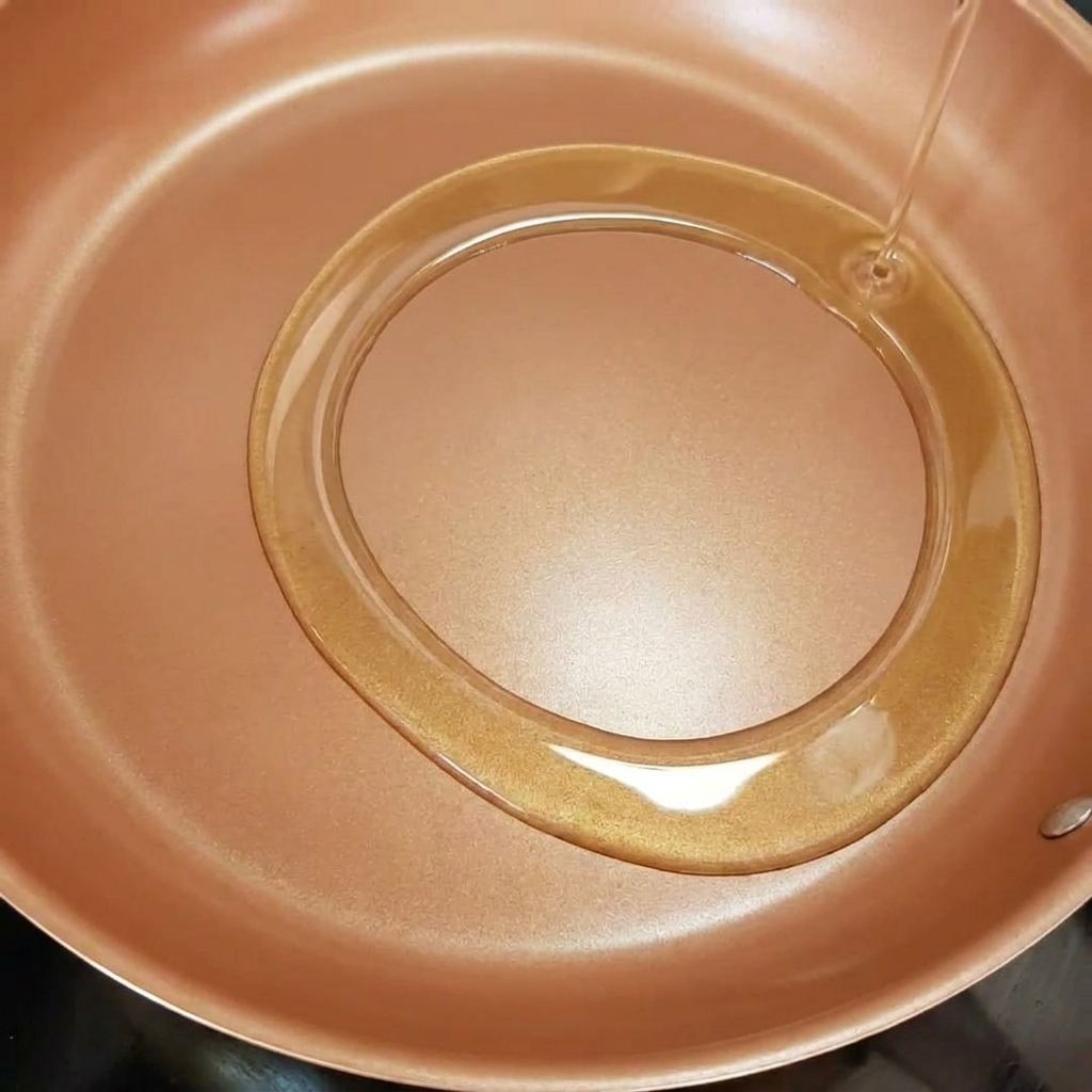 オリーブオイルを引いたフライパンで玉ねぎを炒めている様子