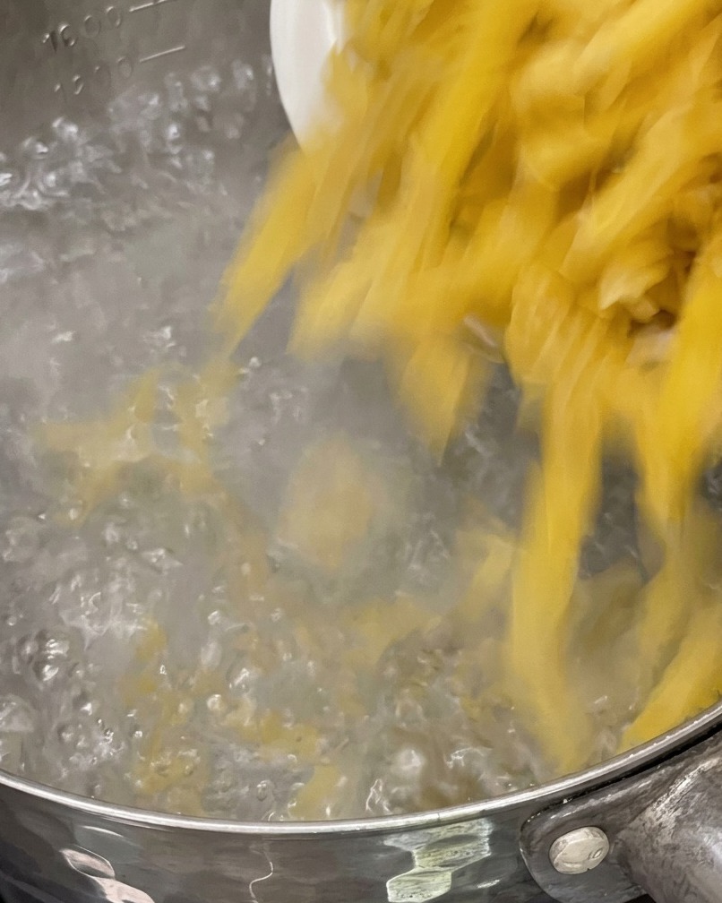 沸騰した鍋にパスタを入れている様子。