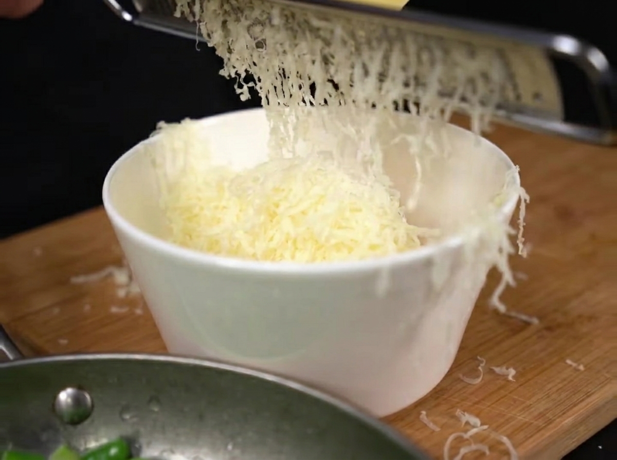 卵黄の入ったボウルにパルメザンチーズをすりおろしている様子。