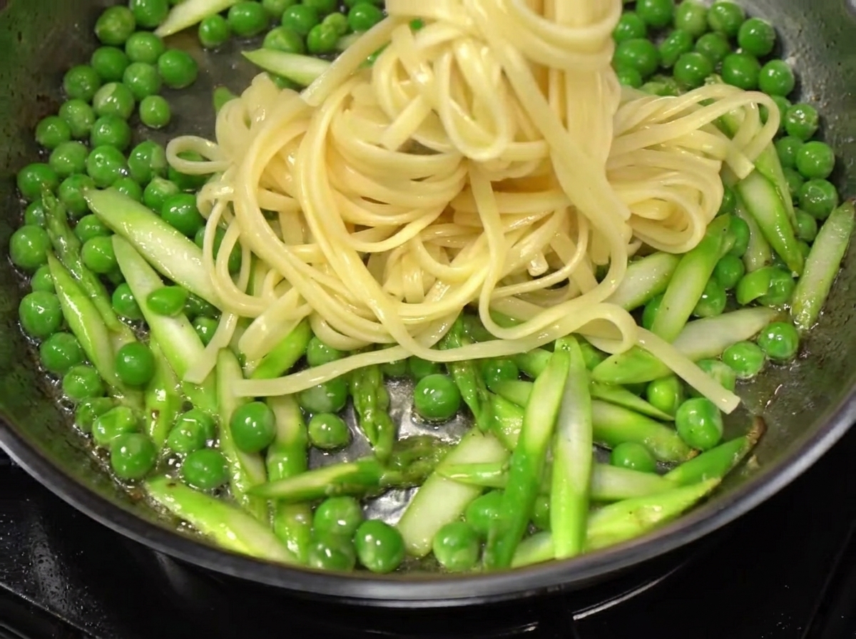 茹でたパスタをフライパンに移し、野菜と絡めている様子。