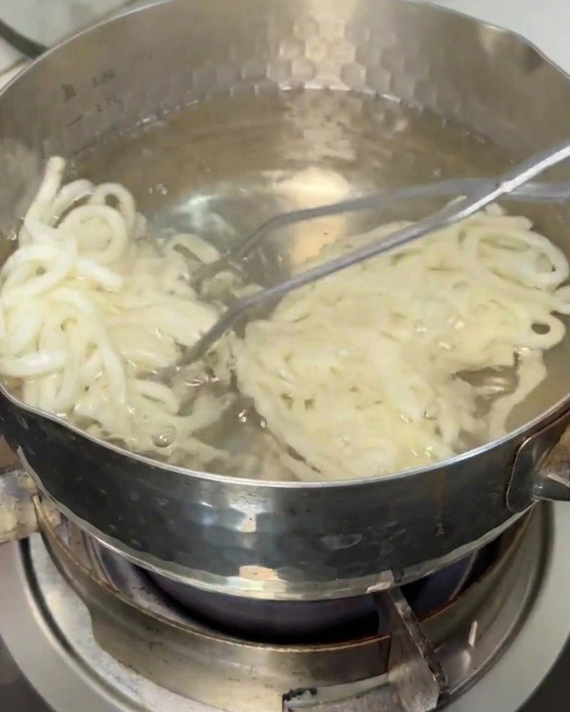 茹で上がったうどんをザルですくい上げている様子。