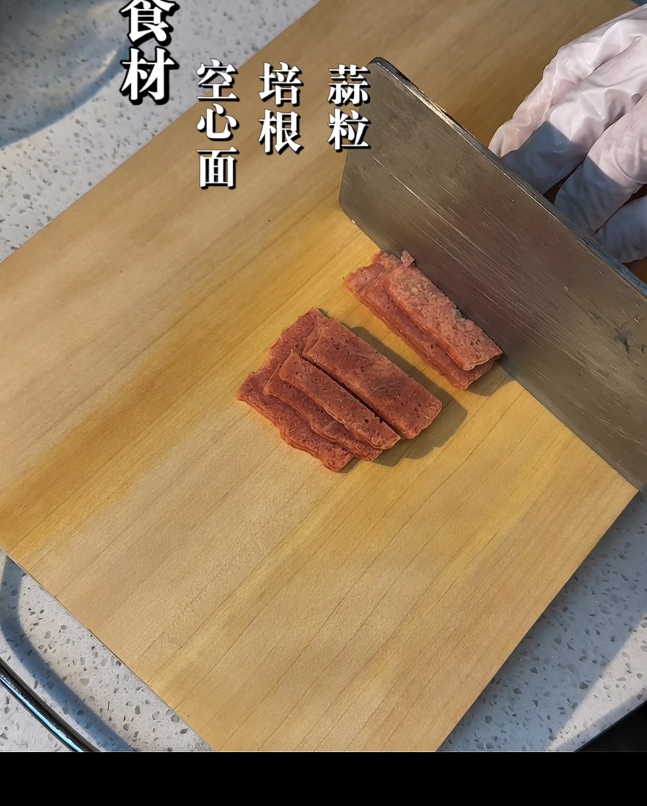 木のまな板の上でベーコンを一口大に切っている様子。