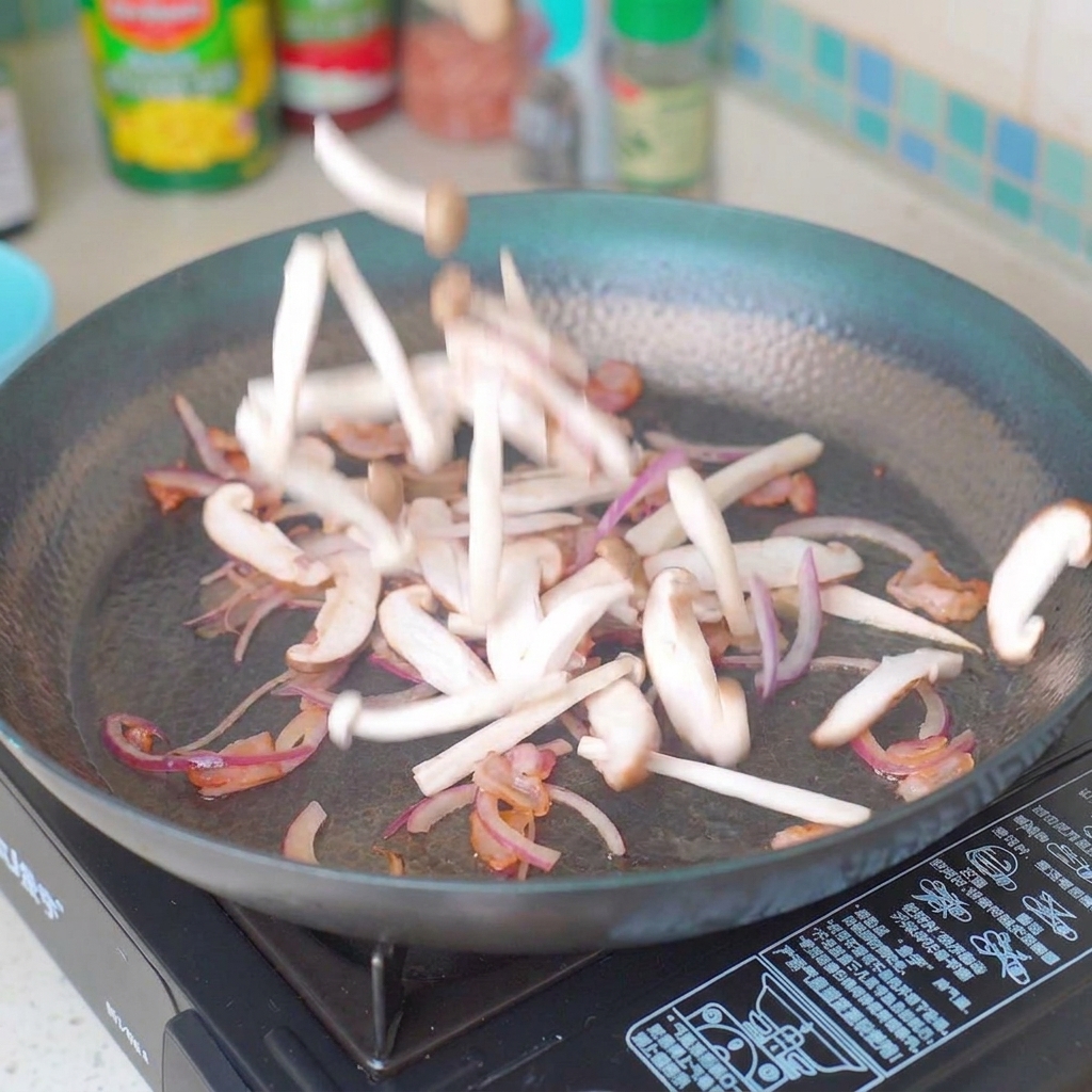 スライスしたキノコと玉ねぎをベーコンと一緒に炒めている様子