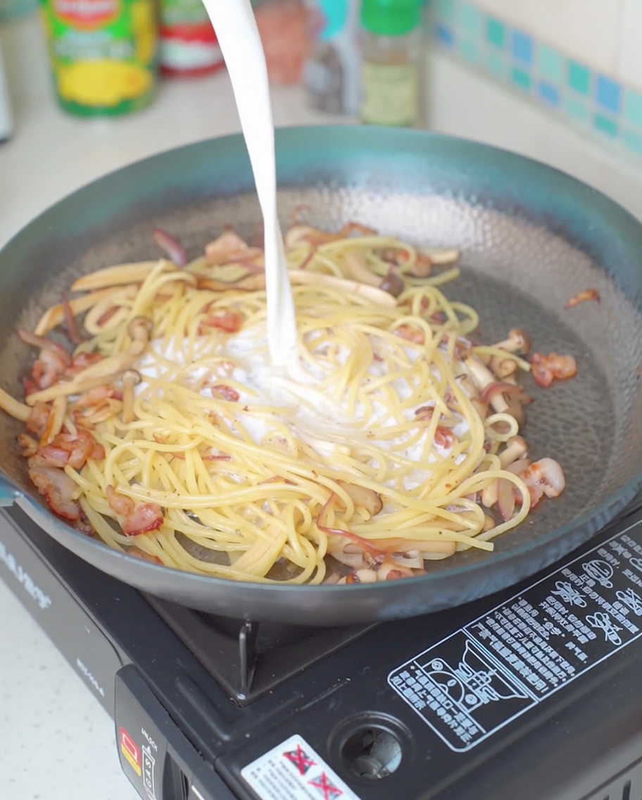 パスタに牛乳を注ぎ入れている様子