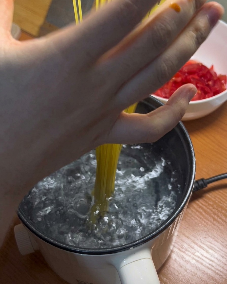沸騰した鍋にパスタを入れる様子