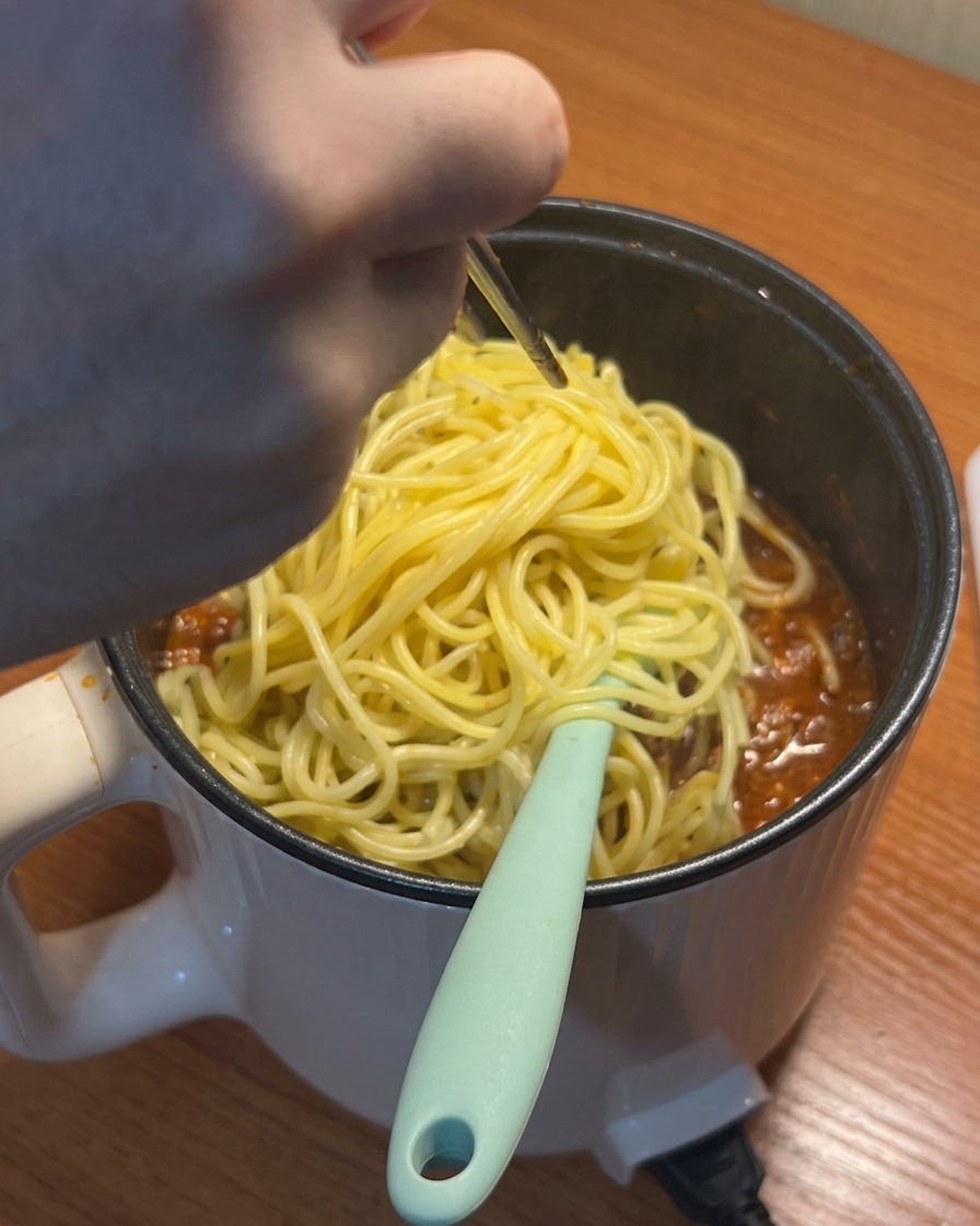 パスタをソースの入った鍋に入れる様子