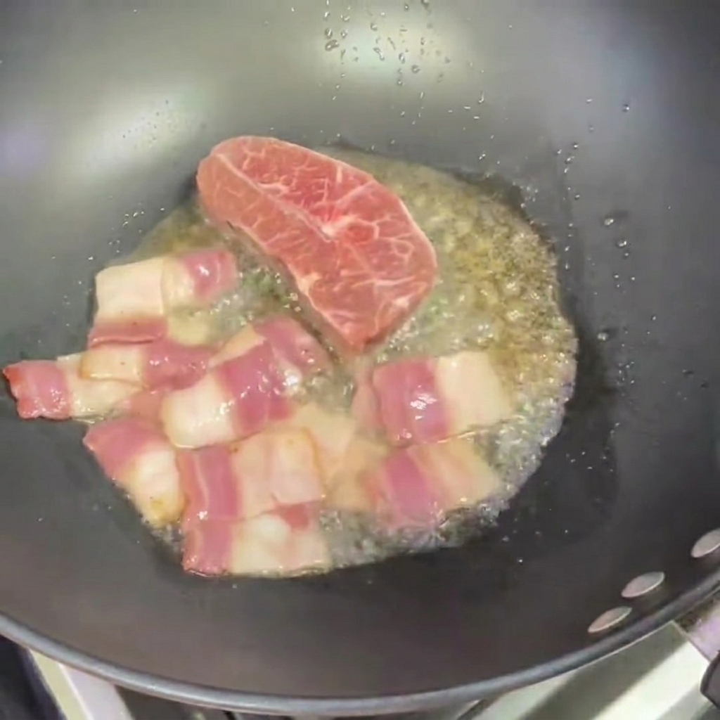 ベーコンの隣で2枚の小さなステーキを焼いている中華鍋。