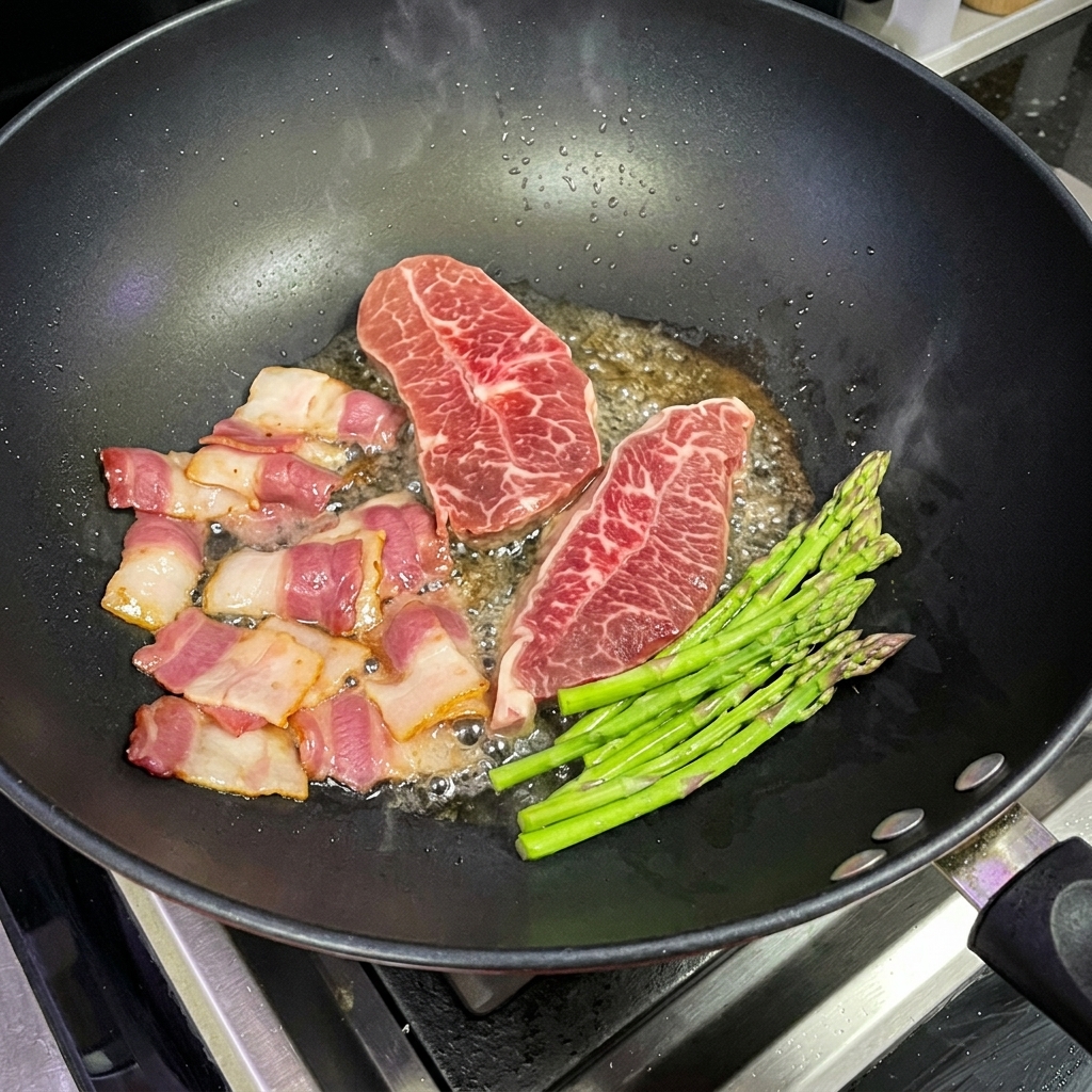 ステーキやベーコンと一緒に中華鍋で炒められる新鮮なアスパラガス。