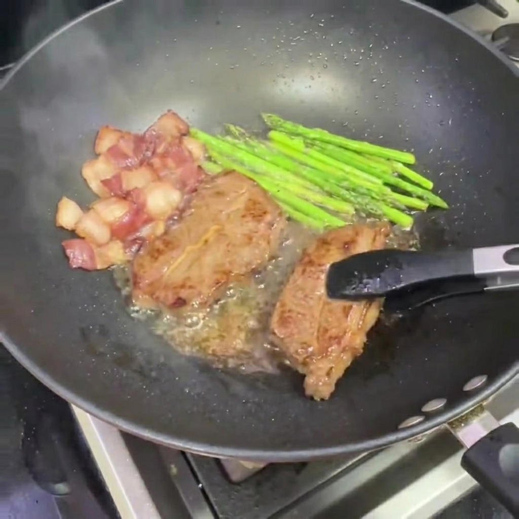 トングで焼けたステーキを中華鍋から取り出している様子。