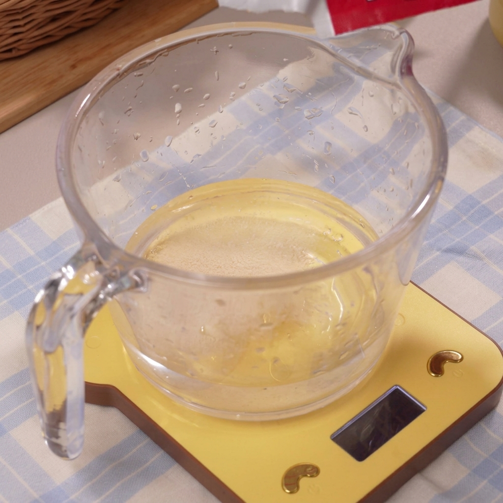 計量カップに入った透明な氷水に溶けていくイースト。