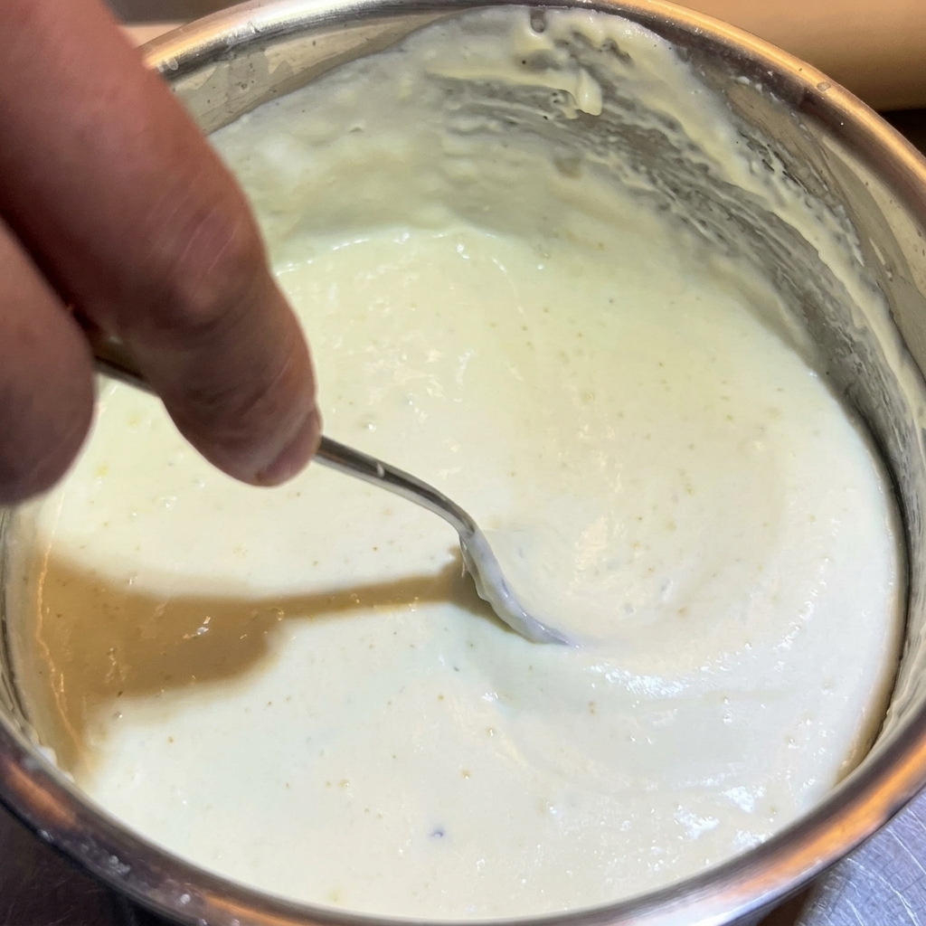 鍋の中でスプーンを使ってソースをかき混ぜている様子。