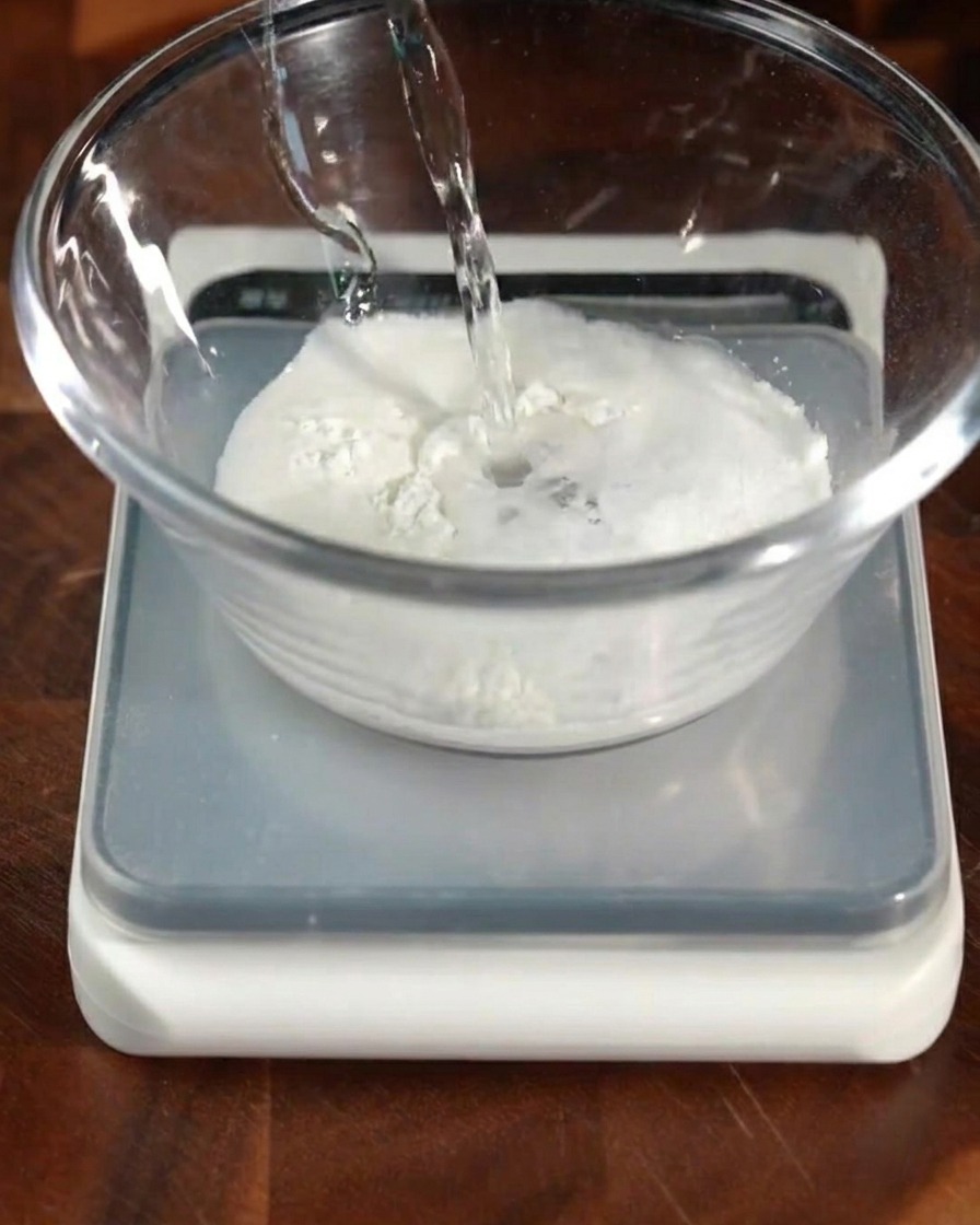 小麦粉などの粉類が入ったボウルに、温かいイースト液を注いでいる様子。
