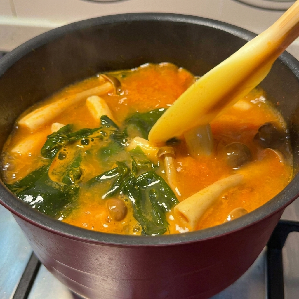 こんがり焼かれたサーモンが味噌スープの鍋に加えられている様子。