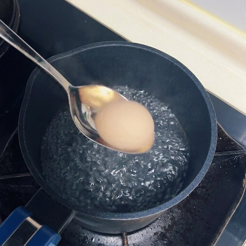 沸騰したお湯の中にスプーンでそっと入れられる卵。