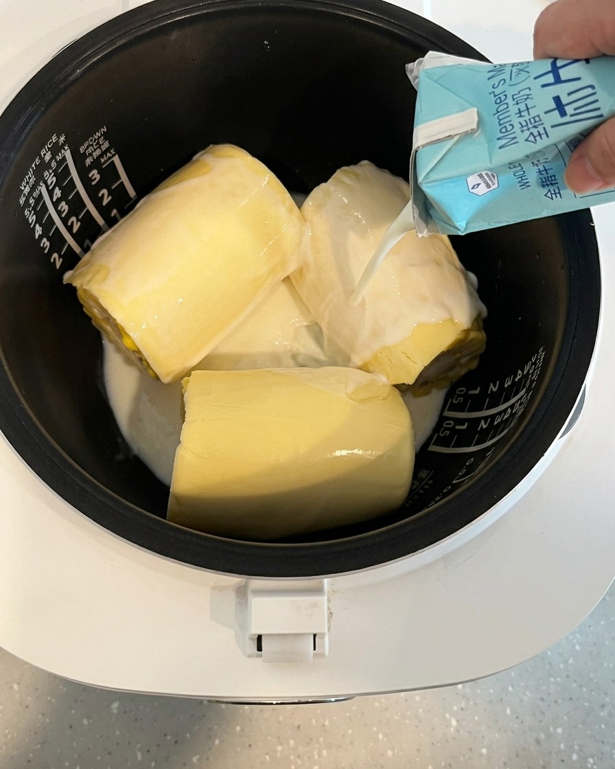 牛乳をとうもろこしとチーズが入った炊飯釜に注いでいる様子。