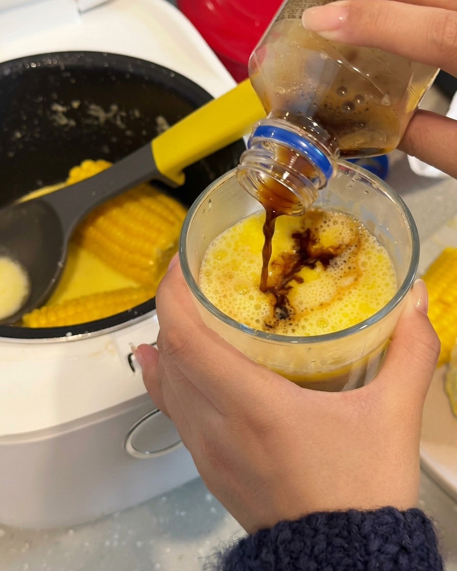 コーヒーをコーンスープの入ったグラスに注いでいる様子。