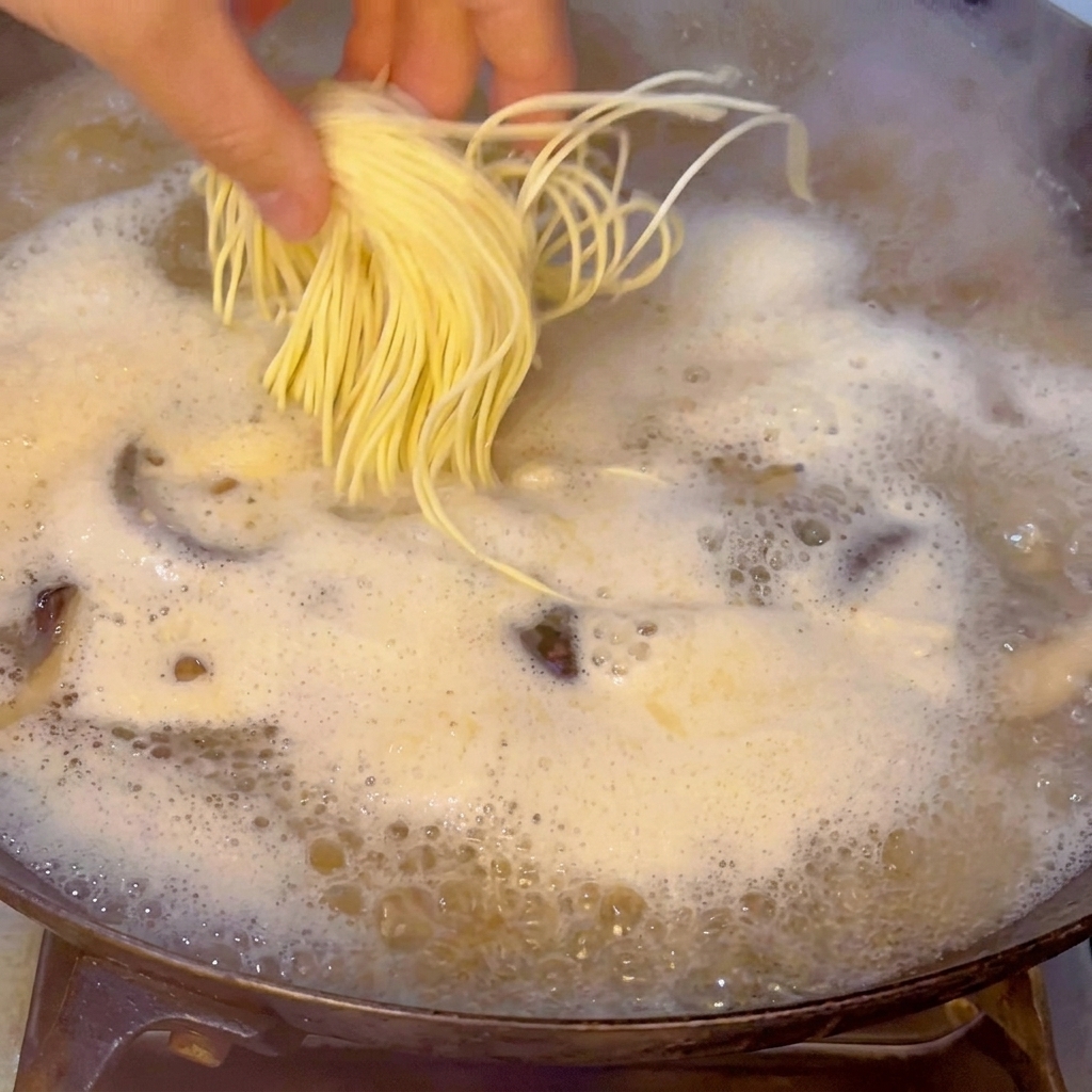 沸騰したスープに生ラーメンを入れている様子。