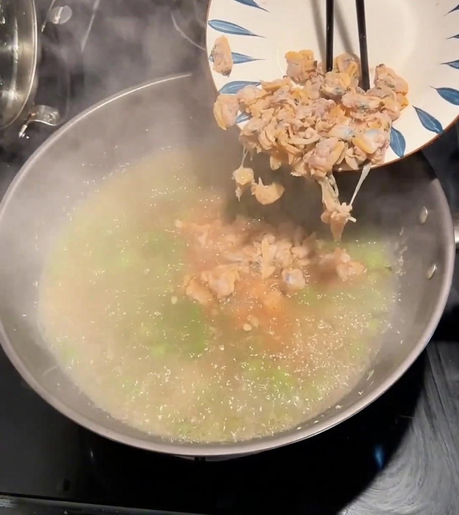 調理中のスープにあさりの身を加えている様子。