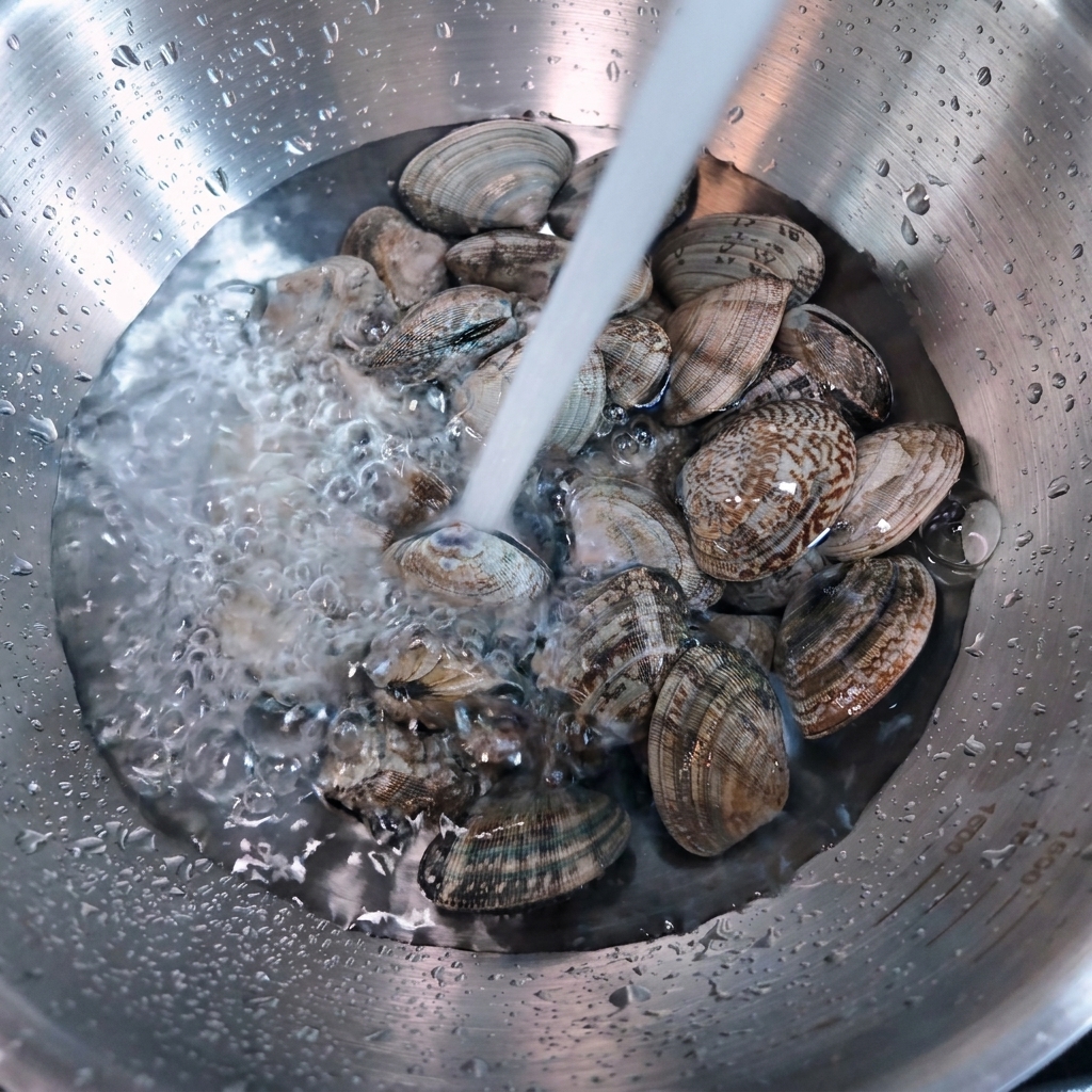 ボウルに入ったあさりに水を注いでいる様子。