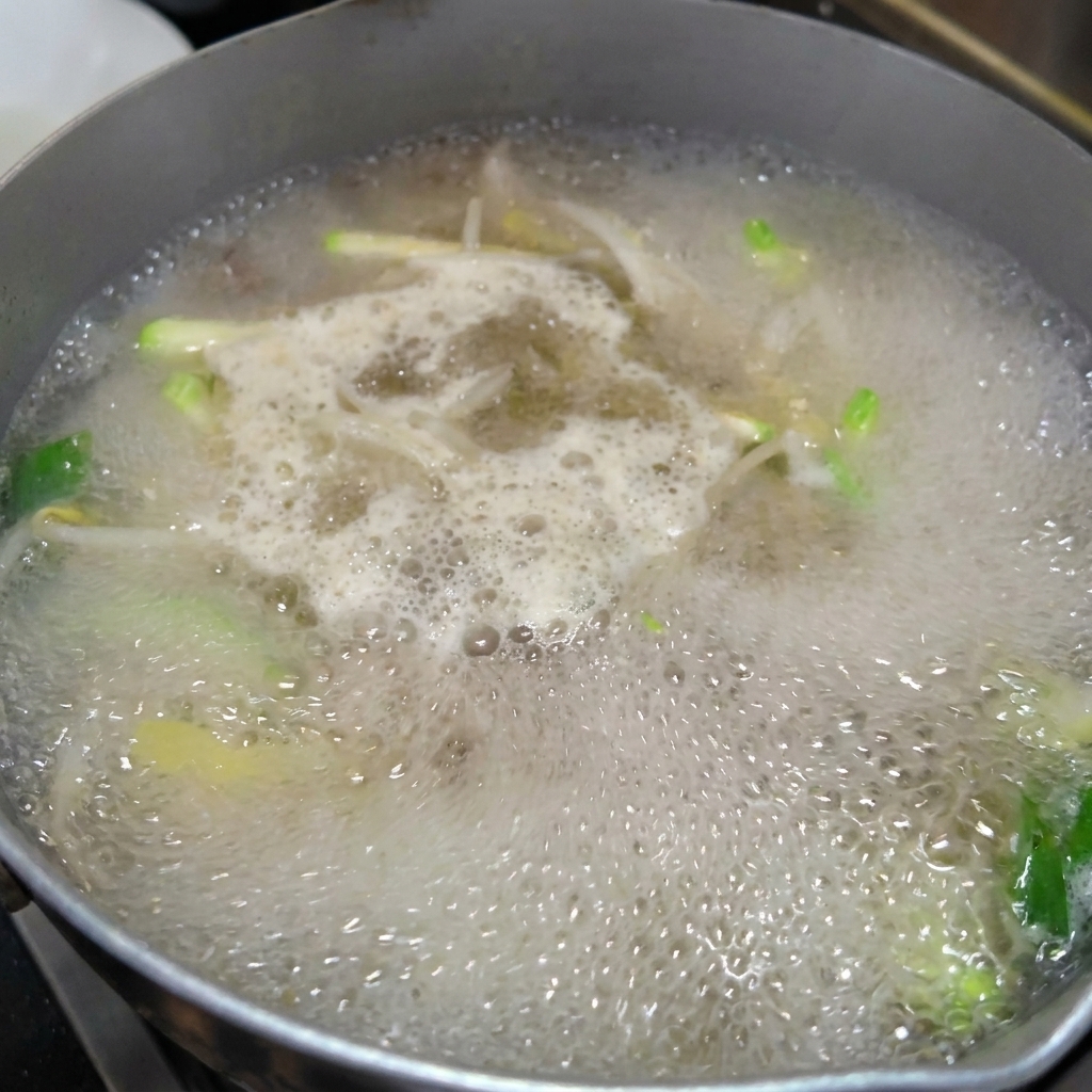 野菜とあさりのだしが効いたスープに手延べ麺を入れている様子。